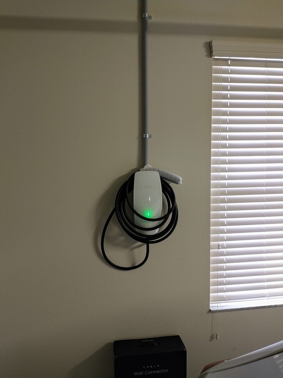 A home EV wall charger with the cable coiled beside it